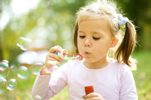 Little girl is blowing a soap bubbles